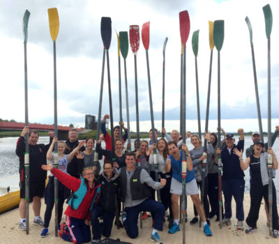 Many people smiling to the camera after rowing