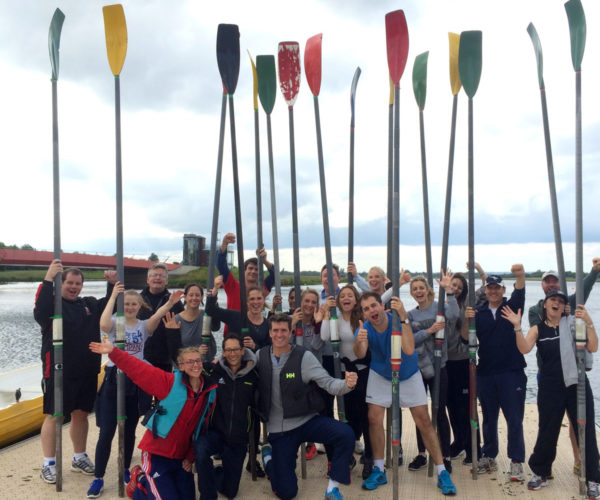 Many people smiling to the camera after rowing